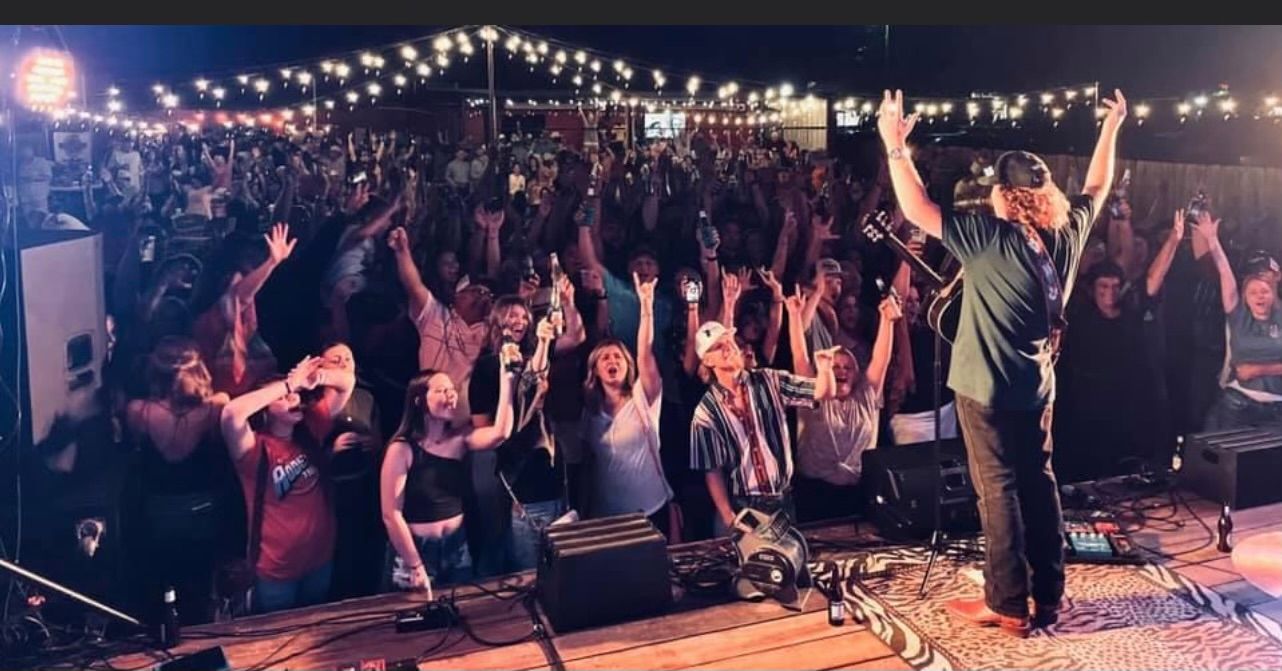 Live band performing at dive bar Big's Mayberry Tavern outdoor stage in Texas.